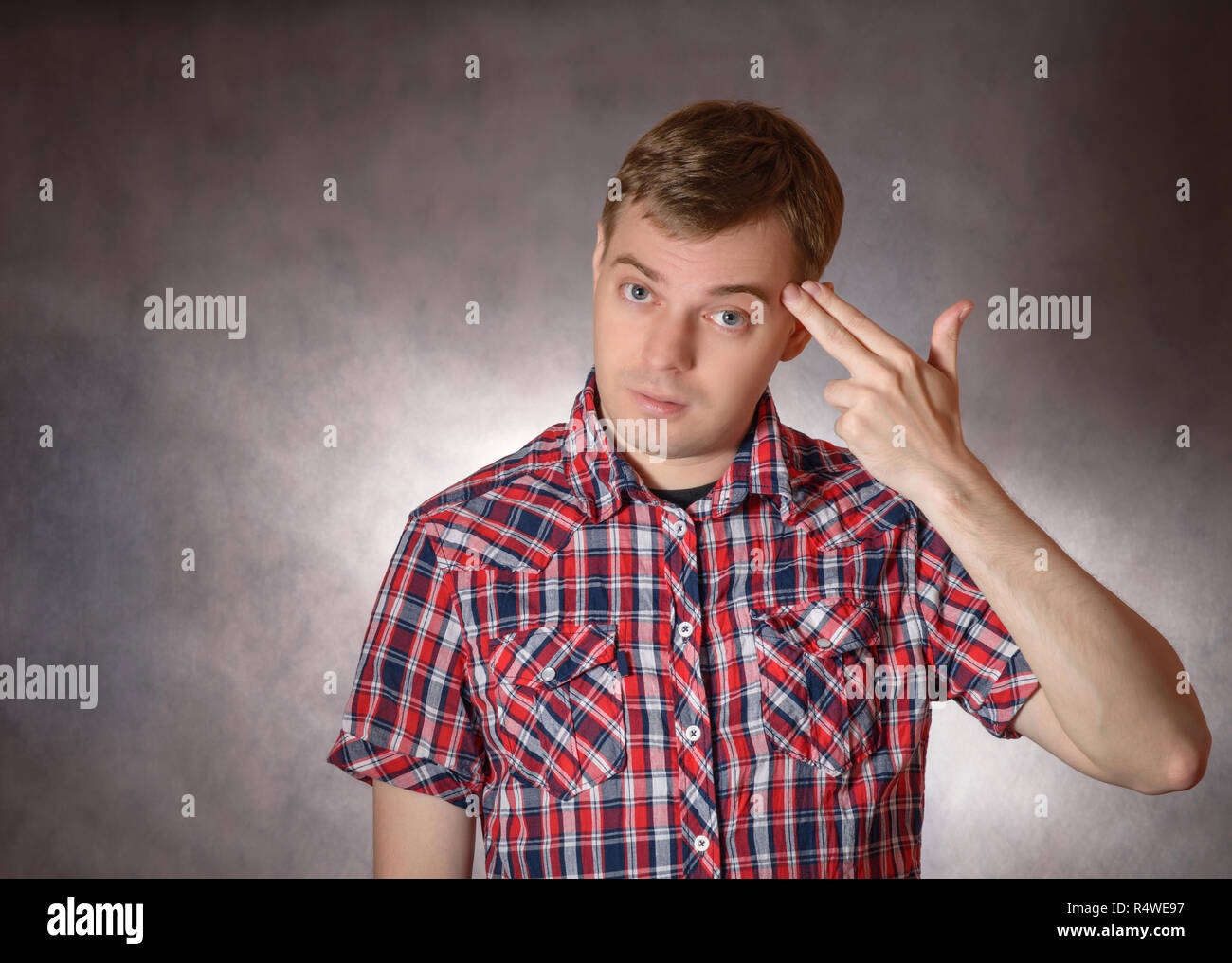 Junge Mann zeigt Headshot mit seinen Fingern. Stress oder Depression Konzept. Stockfoto