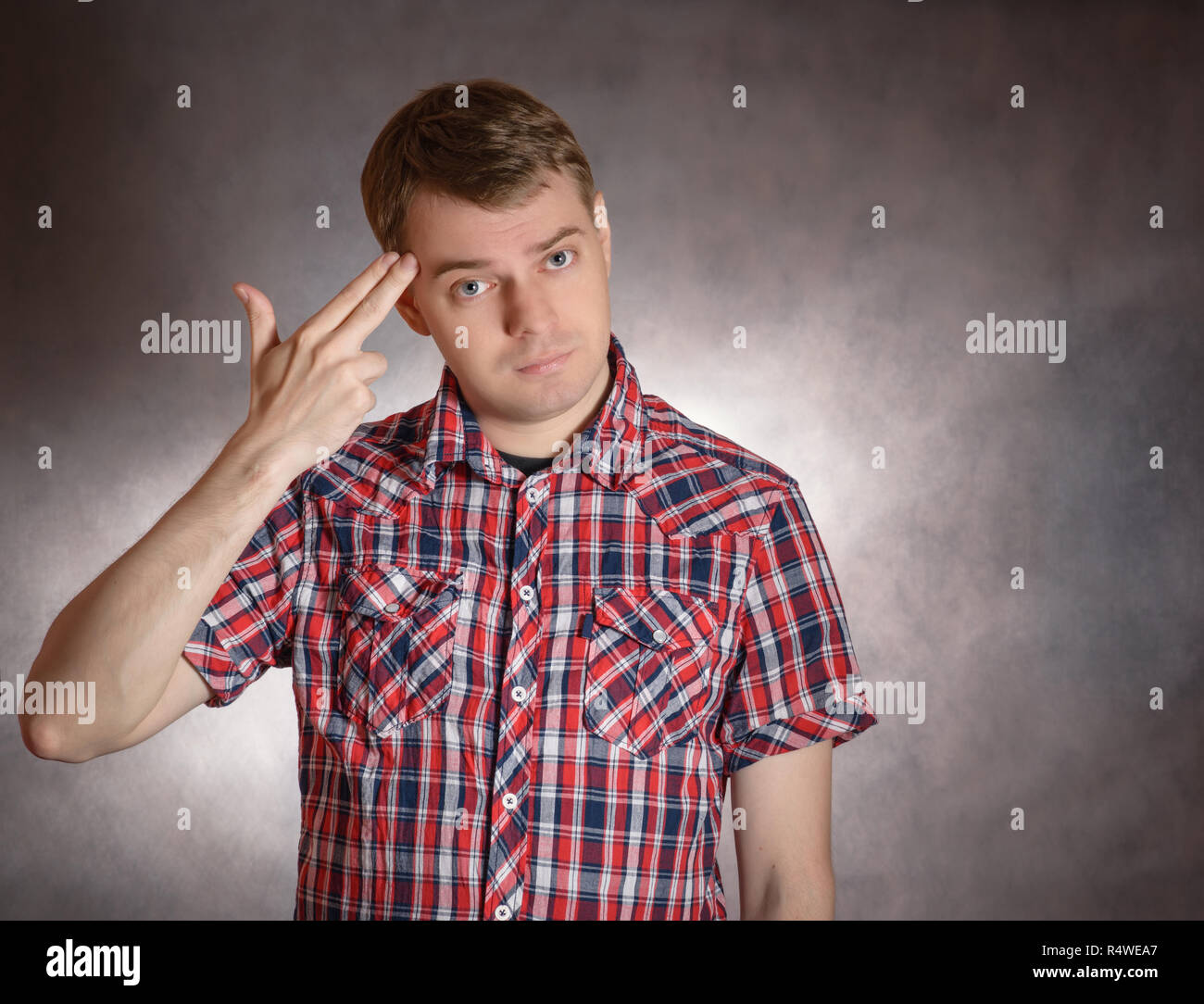 Junge Mann zeigt Headshot mit seinen Fingern. Stress oder Depression Konzept. Stockfoto