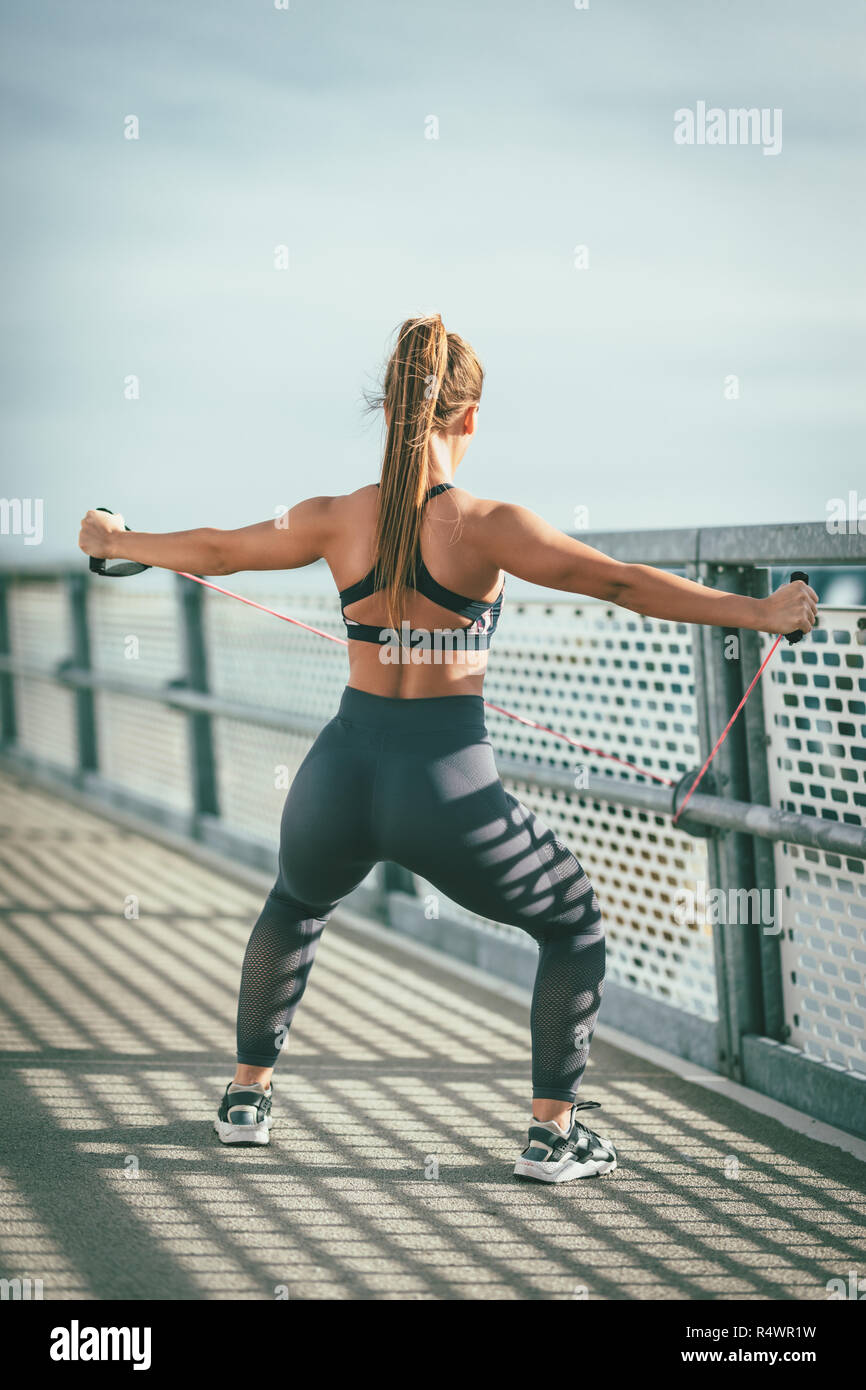 Muskulöse junge Frau tut gut geeignet sind Körper Training mit elastischen Gummiband auf der Brücke. Stockfoto