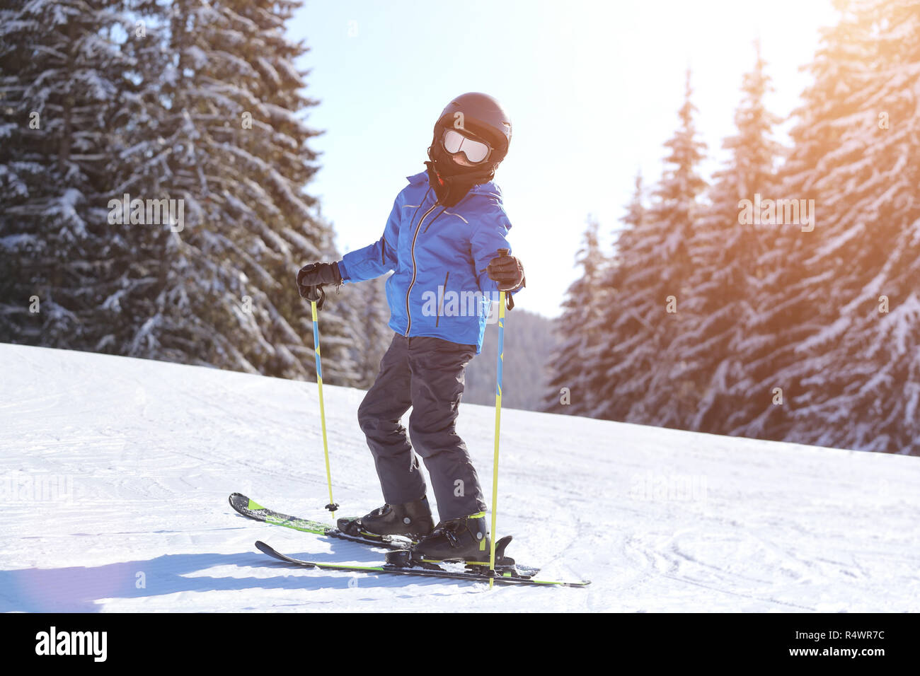 Kleine Jungen im Helm Skifahren auf der Piste bei Mountain Ski Resort Stockfoto