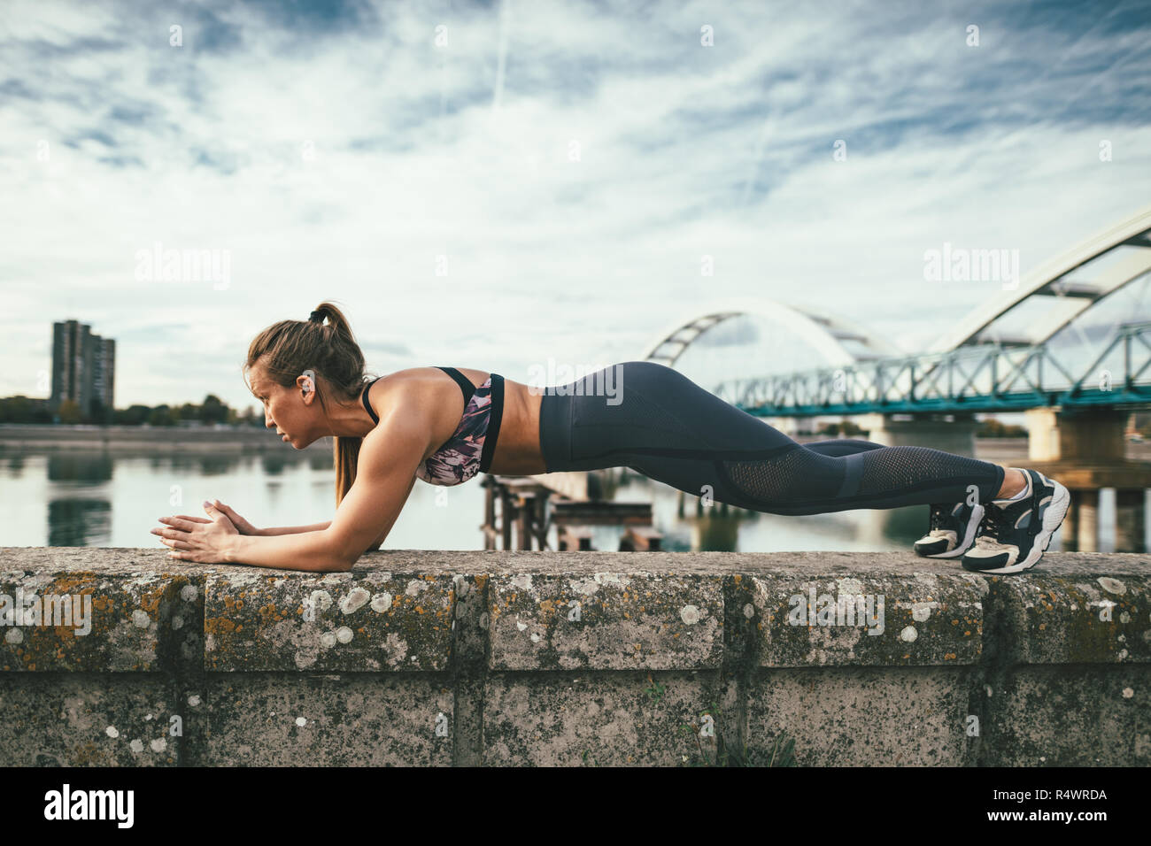 Young Sport Frau tun plank Übung auf der Wand während outdoor Cross Training durch den Fluss fokussiert. Stockfoto