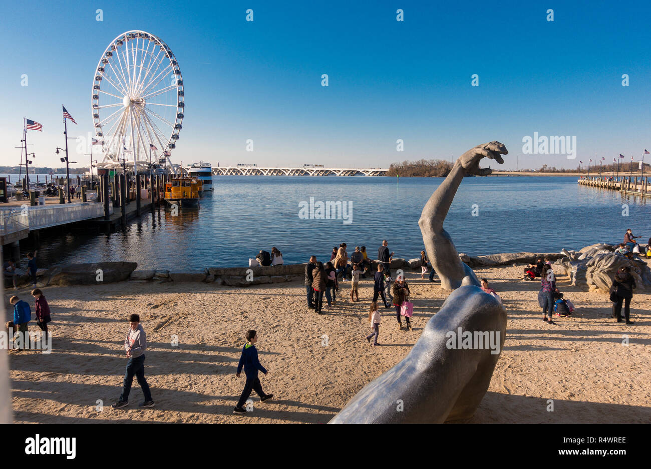 NATIONAL Harbor, Maryland, USA - Das Erwachen Skulptur und die Leute am Strand, mit Hauptstadt Rad Fahrgeschäft auf der linken Seite. Stockfoto