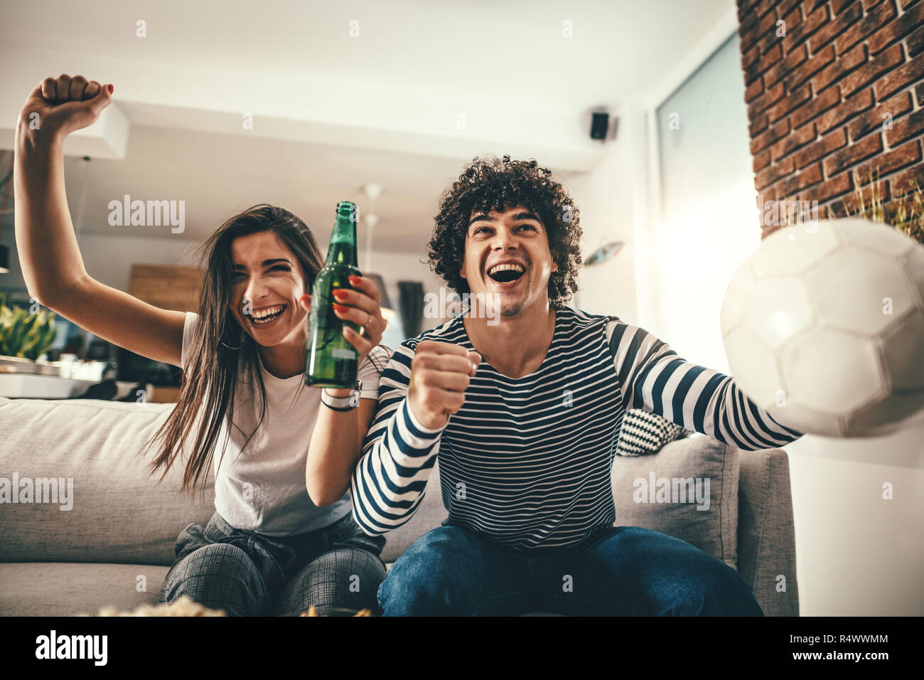 Paar sind Fans von Sport Spiele wie Fußball lieben ihre Freizeit zu Hause zusammen. Sie sind Schreiend und gestikulierend für einen Sieg. Stockfoto