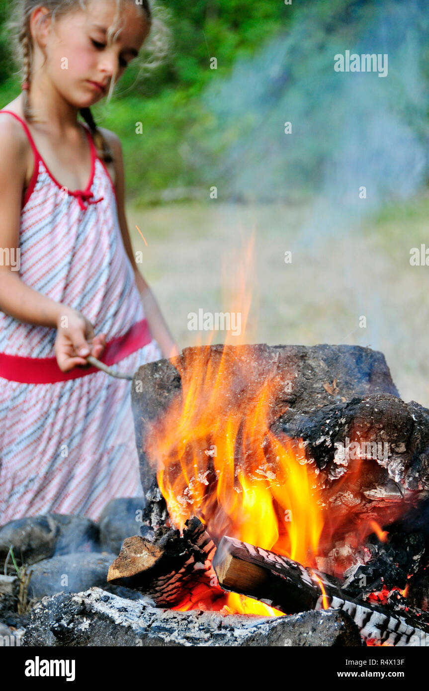 Ein junges Mädchen spielen mit einem Lagerfeuer Stockfoto