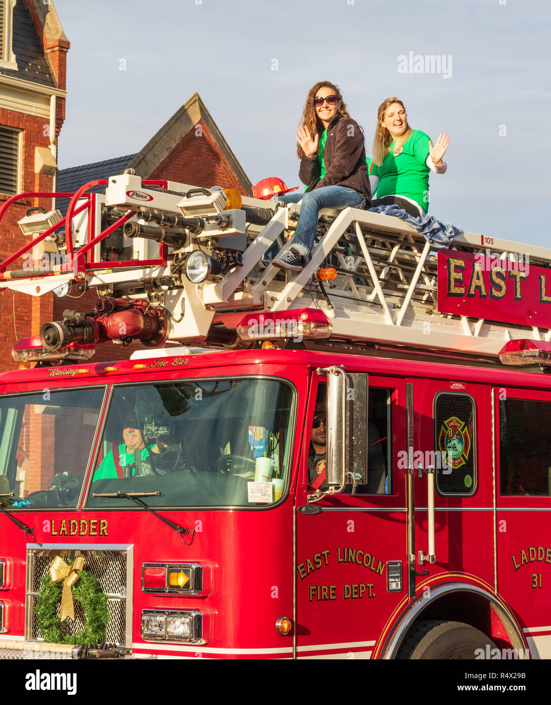 Mebane, NC, USA -11/25/18: Zwei junge Frauen fahren und Welle von oben ein Feuerwehrauto Lkw in den jährlichen Christmas Parade. Stockfoto