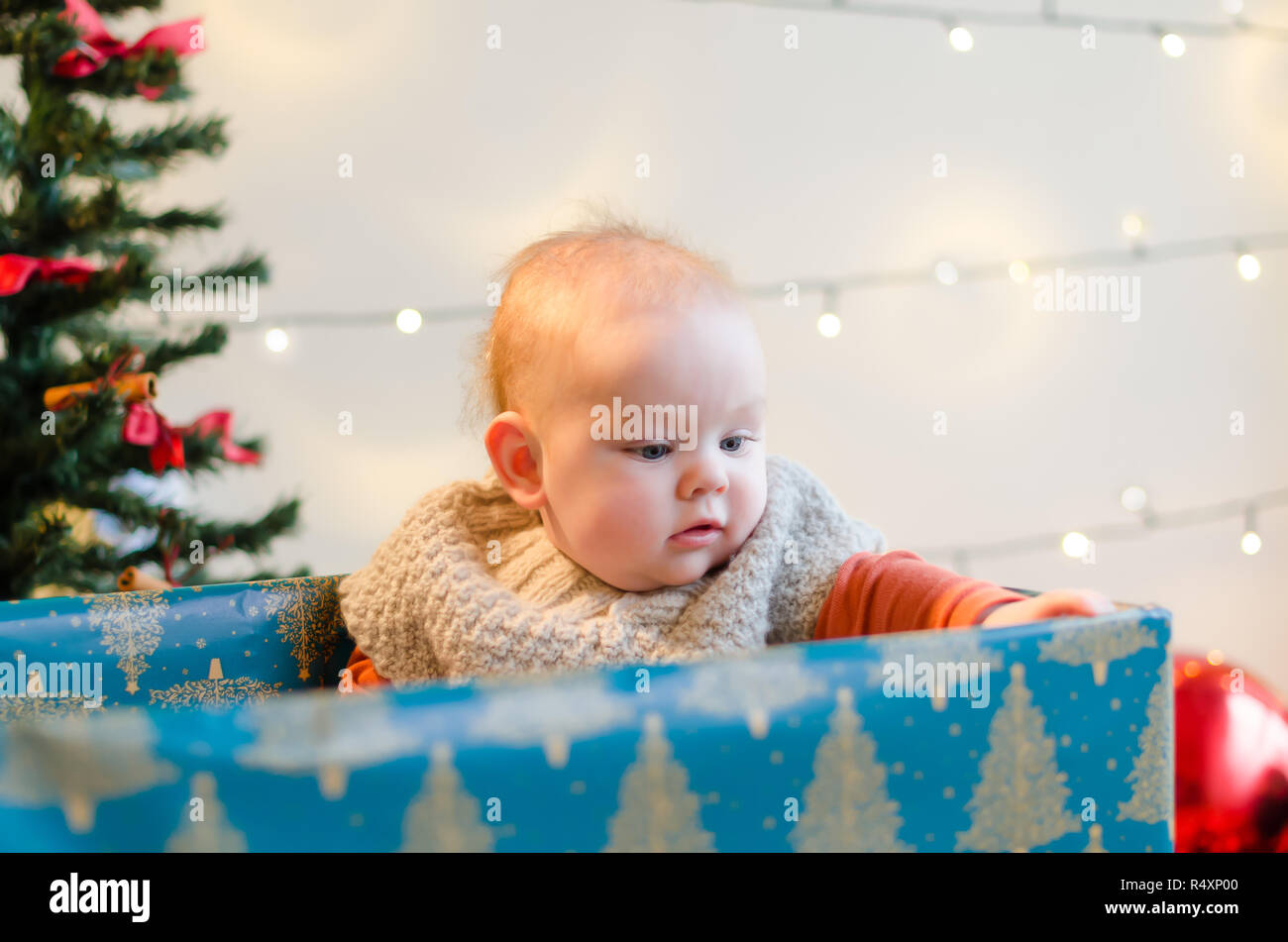 Happy Christmas baby boy in einem derzeitigen Kasten um Weihnachtsbaum und Dekorationen Stockfoto