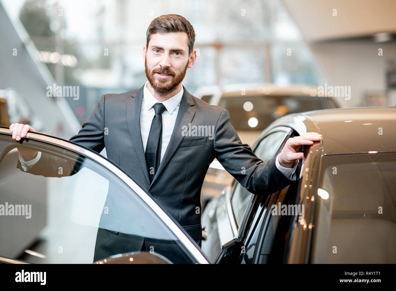 Porträt eines eleganten Geschäftsmann stand in der Nähe des Auto im Showroom Stockfoto