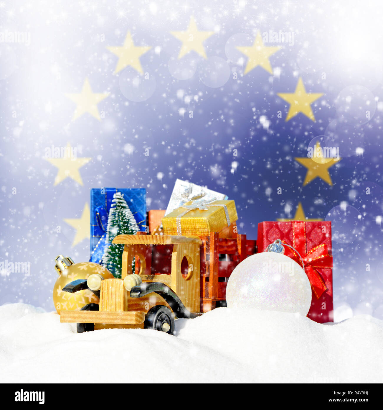 Weihnachten Hintergrund. Spielzeug-LKW mit Geschenken, Neues Jahr Tanne, Kugeln im Schneetreiben und die Fahne der Europäischen Union Stockfoto