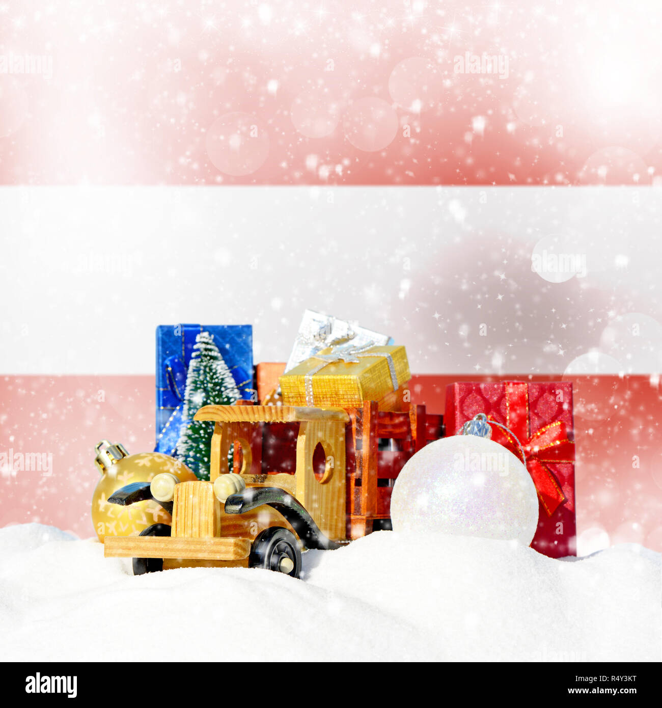 Weihnachten Hintergrund. Spielzeug-LKW mit Geschenken, Neues Jahr Tanne, Kugeln im Schneetreiben und Österreichische Fahne Stockfoto