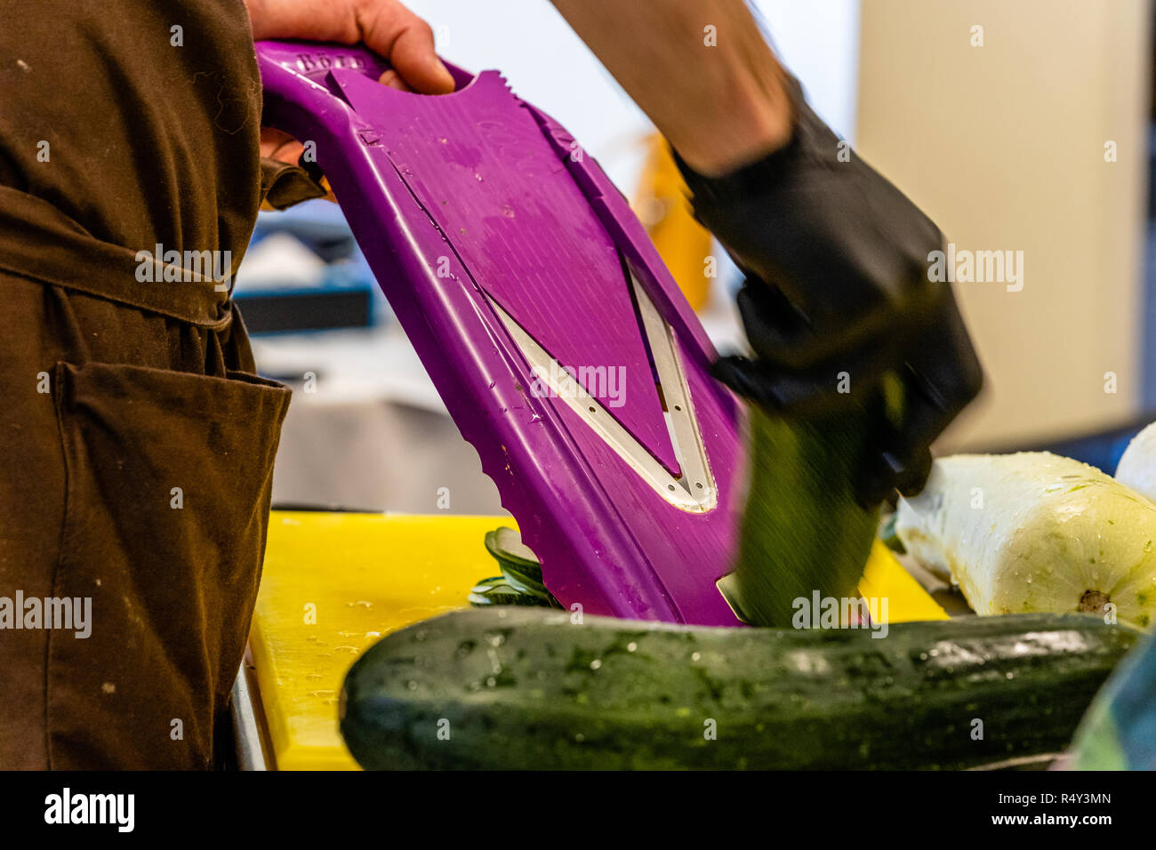 Männliche Chef Schneiden Aubergine in der Küche - mit Handschuh auf seiner Hand Stockfoto