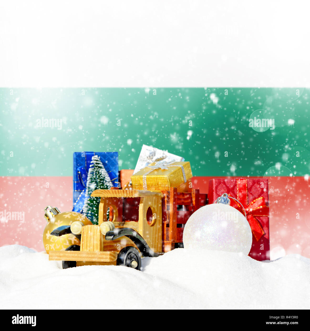 Weihnachten Hintergrund. Spielzeug-LKW mit Geschenken, Neues Jahr Tanne, Kugeln im Schneetreiben und bulgarische Flagge Stockfoto