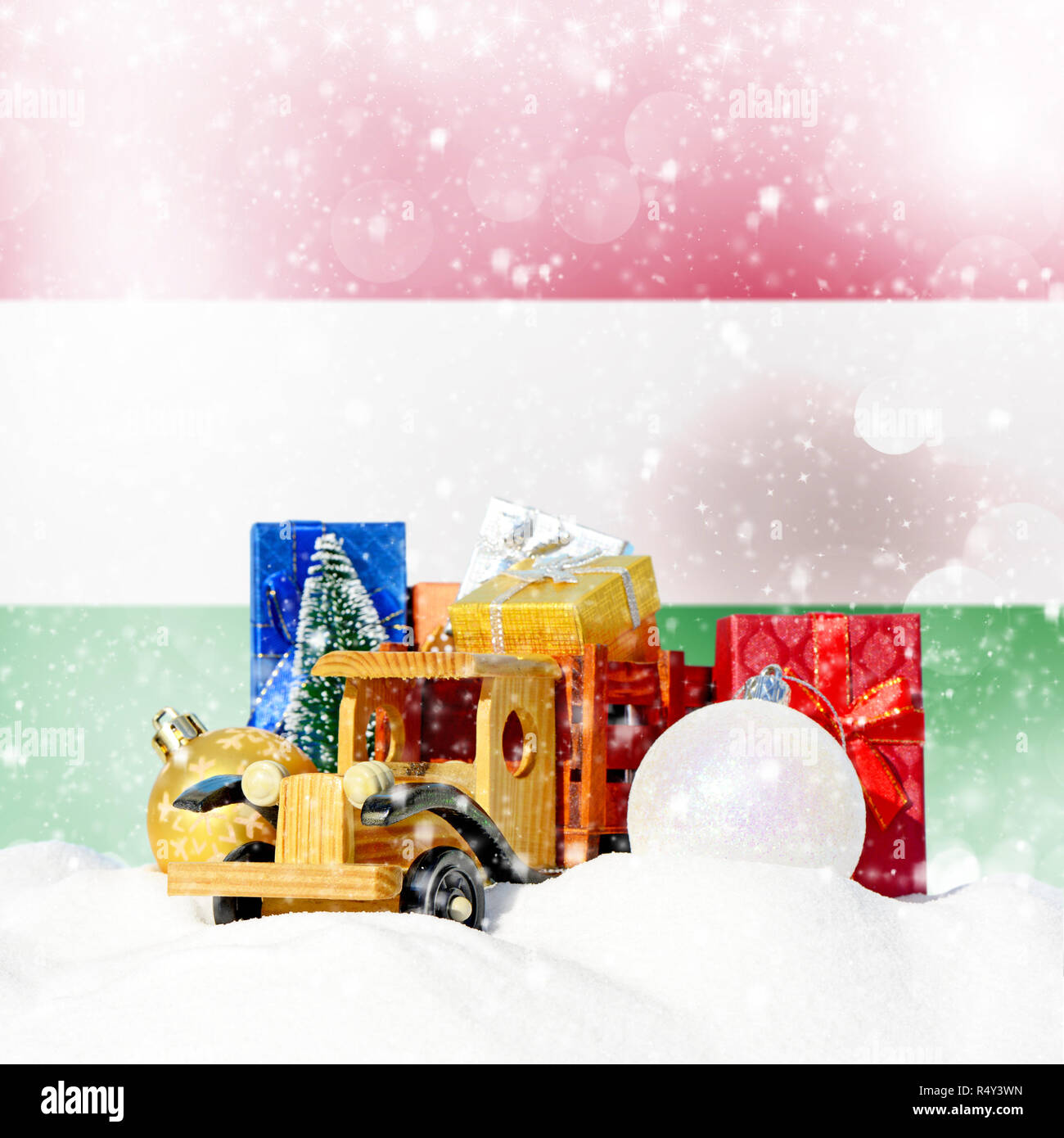 Weihnachten Hintergrund. Spielzeug-LKW mit Geschenken, Neues Jahr Tanne, Kugeln im Schneetreiben und ungarische Flagge Stockfoto