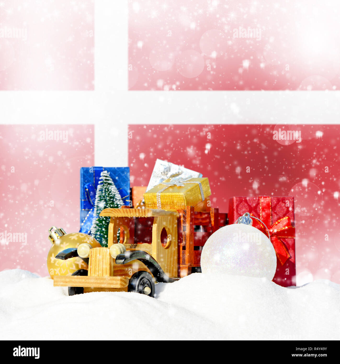 Weihnachten Hintergrund. Spielzeug-LKW mit Geschenken, Neues Jahr Tanne, Kugeln im Schneetreiben und dänische Flagge Stockfoto