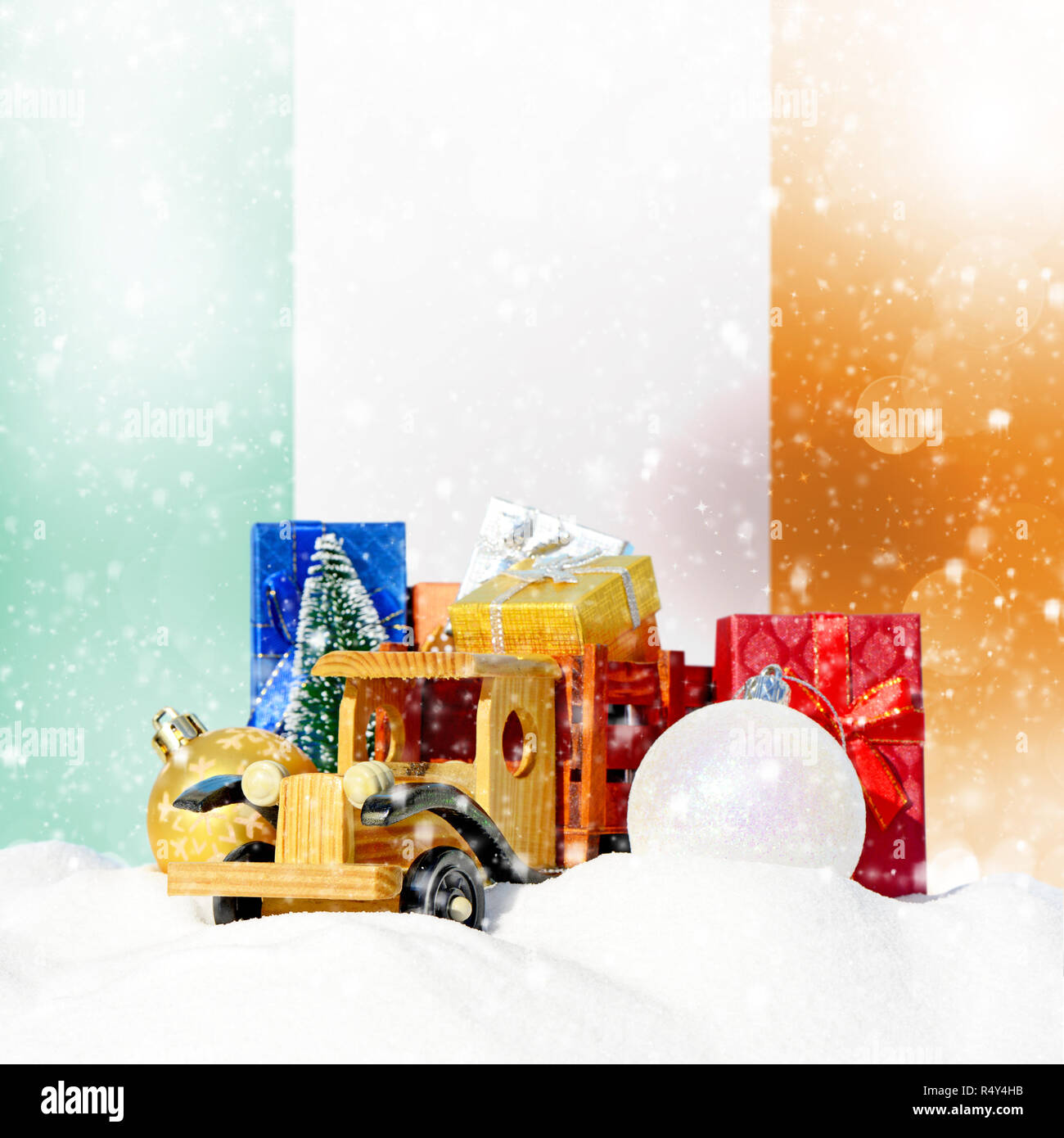 Weihnachten Hintergrund. Spielzeug-LKW mit Geschenken, Neues Jahr Tanne, Kugeln im Schneetreiben und irische Flagge Stockfoto