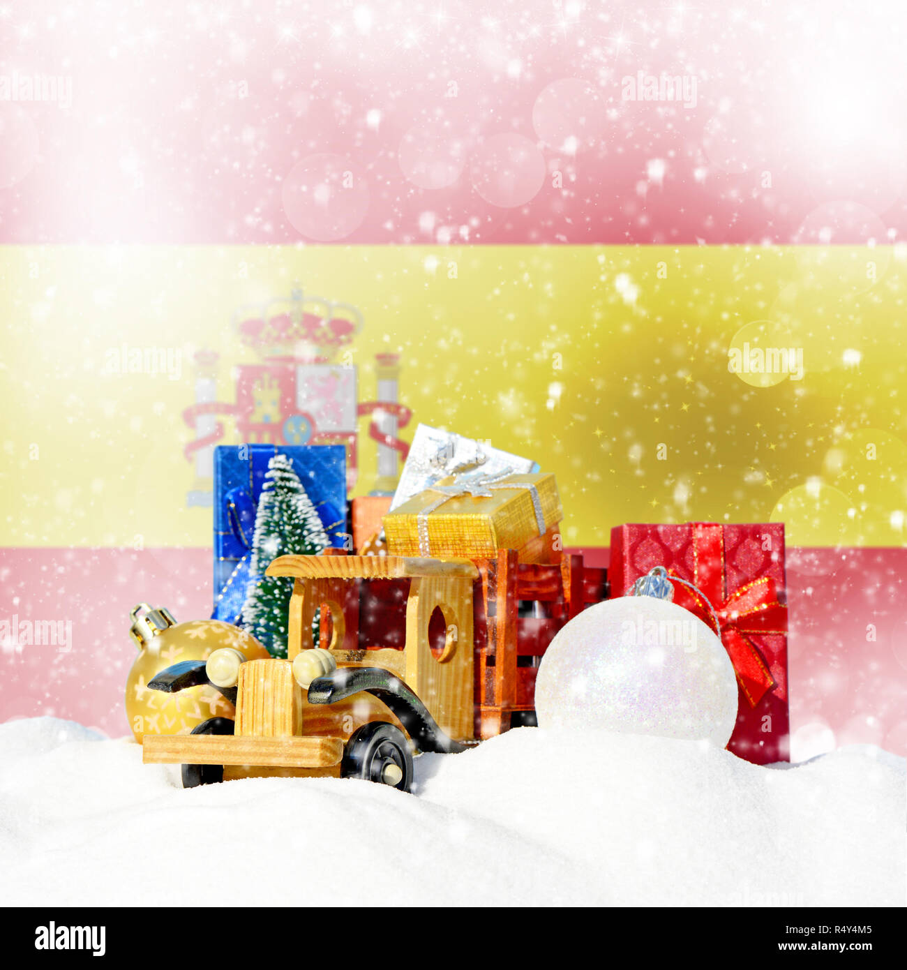 Weihnachten Hintergrund. Spielzeug-LKW mit Geschenken, Neues Jahr Tanne, Kugeln im Schneetreiben und spanische Flagge Stockfoto