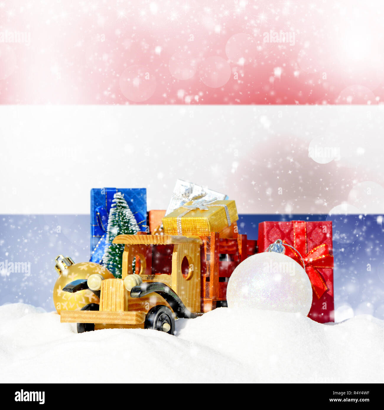 Weihnachten Hintergrund. Spielzeug-LKW mit Geschenken, Neues Jahr Tanne, Kugeln im Schneetreiben und Niederlande Flagge Stockfoto