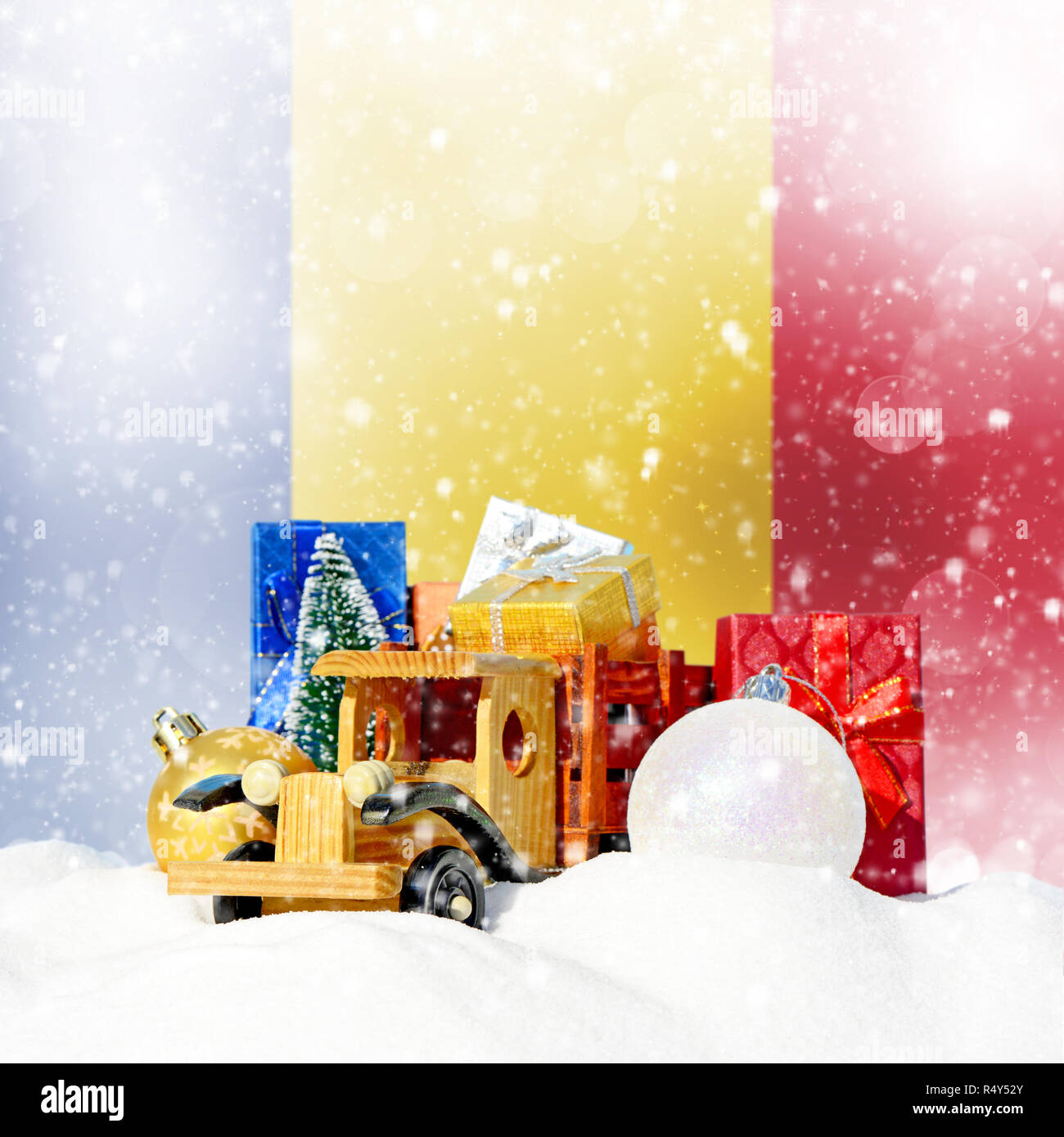 Weihnachten Hintergrund. Spielzeug-LKW mit Geschenken, Neues Jahr Tanne, Kugeln im Schneetreiben und rumänische Flagge Stockfoto