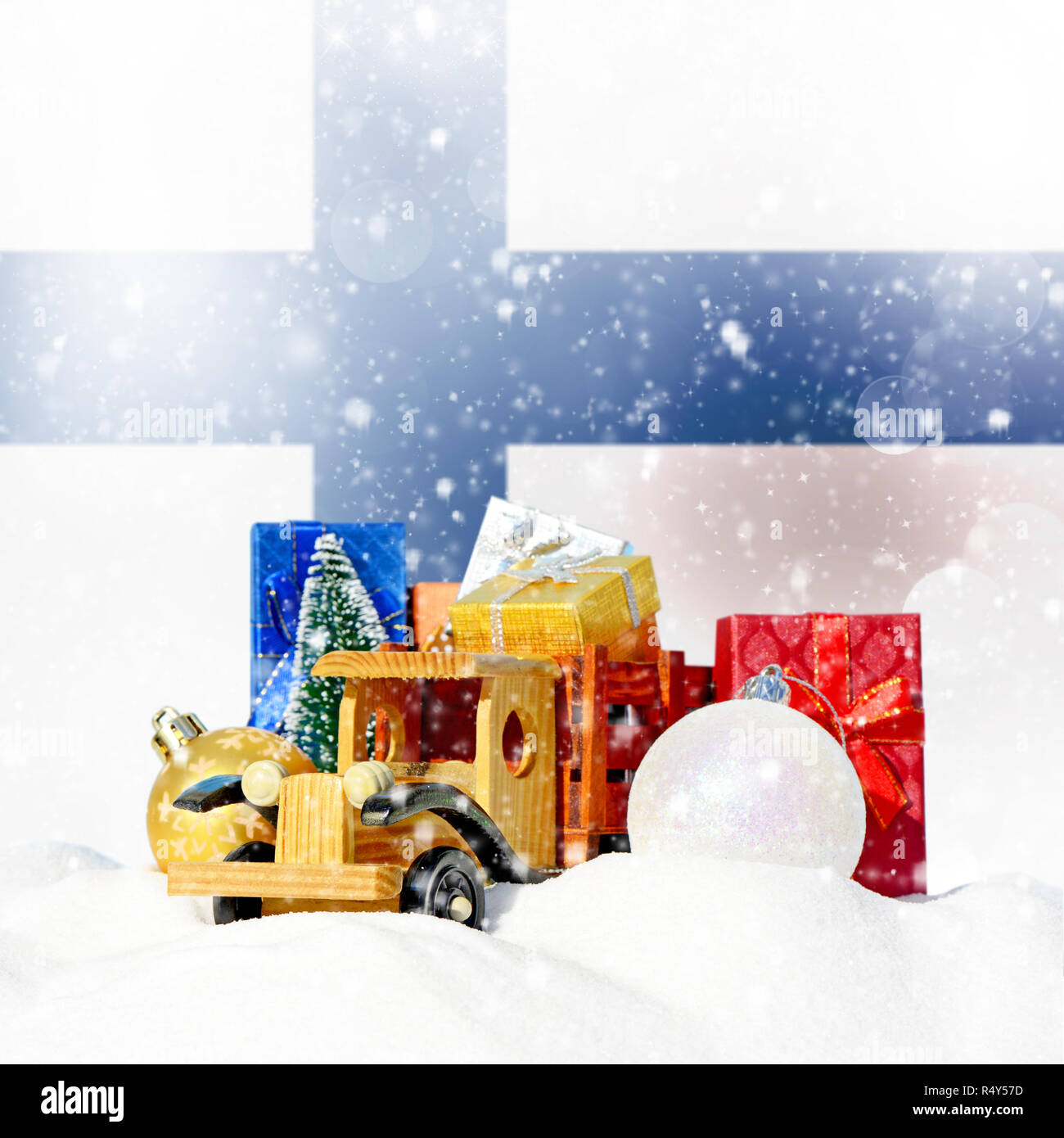 Weihnachten Hintergrund. Spielzeug-LKW mit Geschenken, Neues Jahr Tanne, Kugeln im Schneetreiben und finnische Flagge Stockfoto