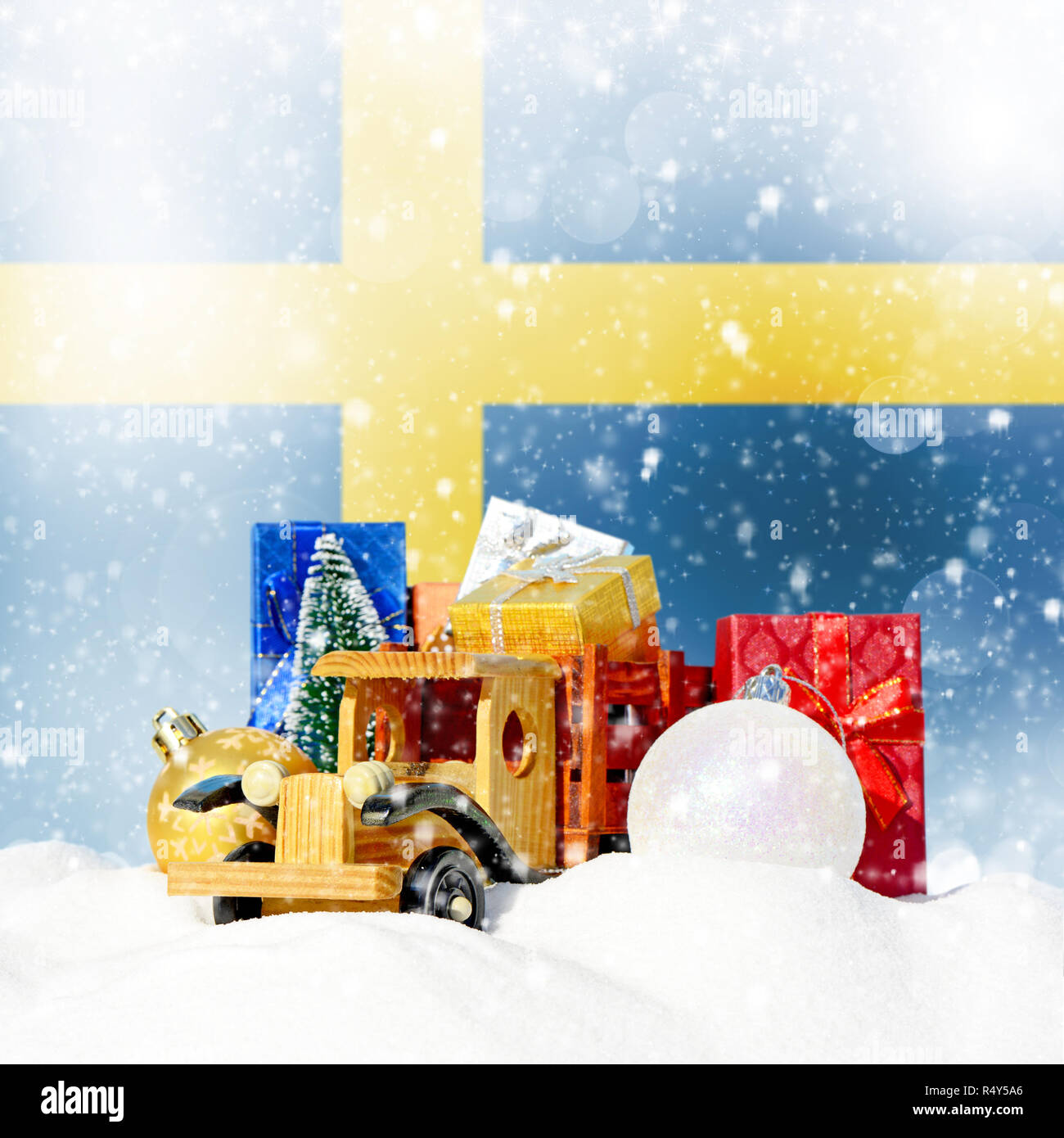 Weihnachten Hintergrund. Spielzeug-LKW mit Geschenken, Neues Jahr Tanne, Kugeln im Schneetreiben und schwedische Flagge Stockfoto