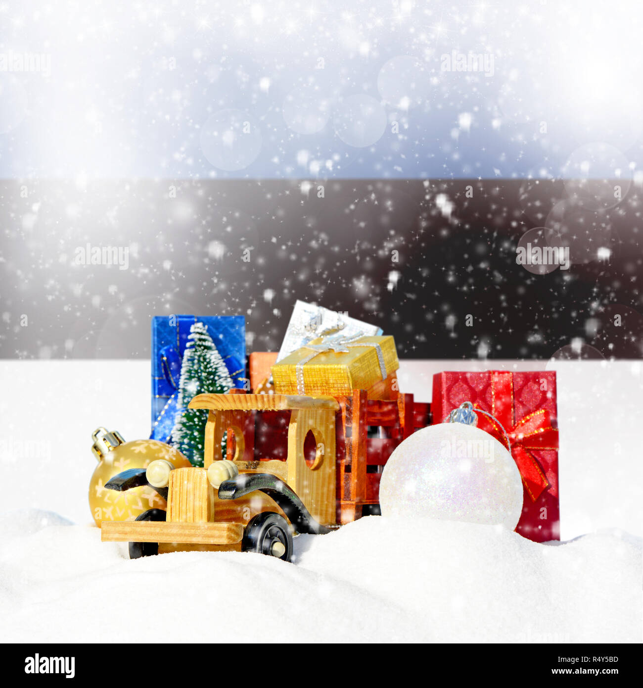 Weihnachten Hintergrund. Spielzeug-LKW mit Geschenken, Neues Jahr Tanne, Kugeln im Schneetreiben und estnische Flagge Stockfoto