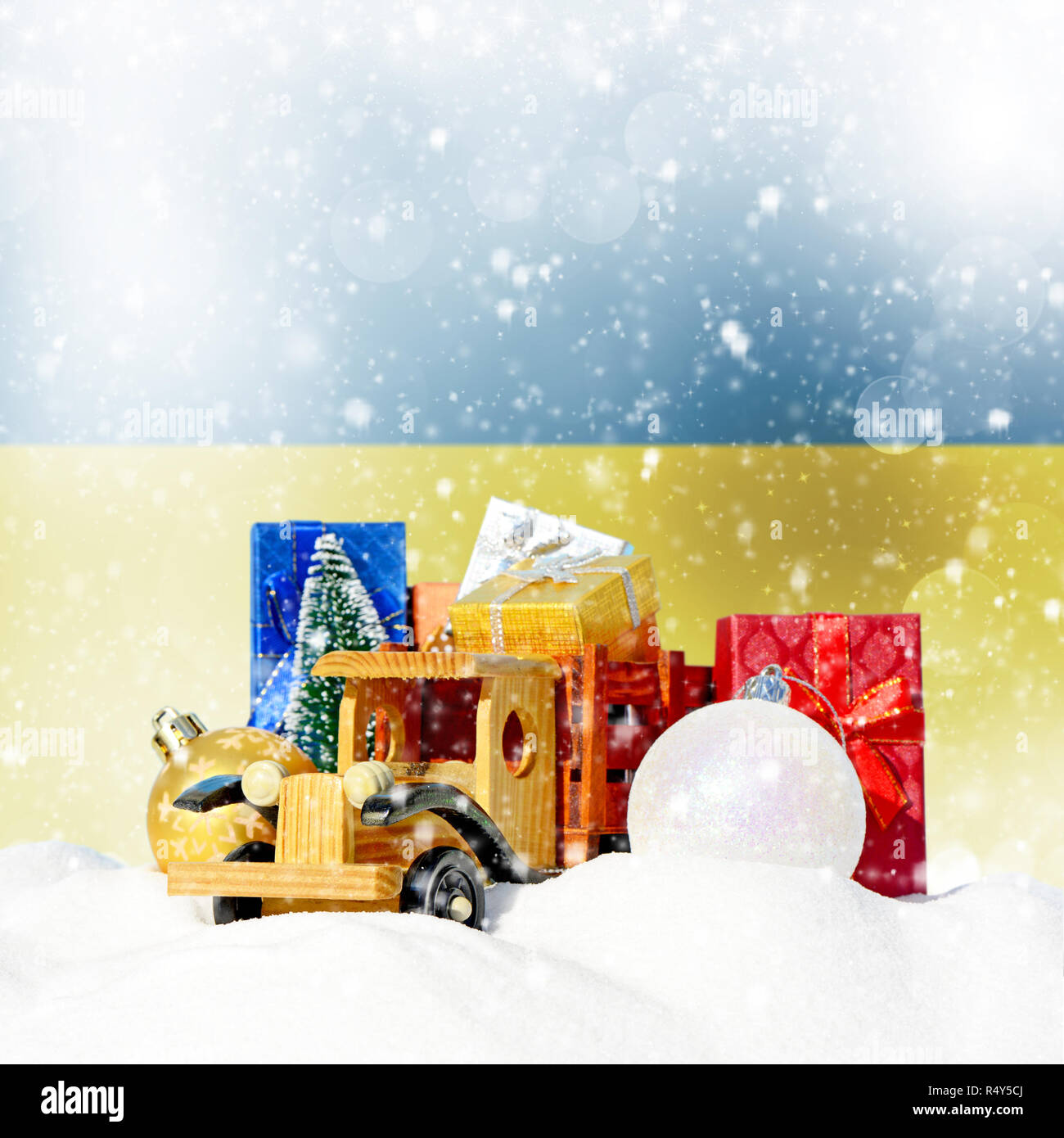 Weihnachten Hintergrund. Spielzeug-LKW mit Geschenken, Neues Jahr Tanne, Kugeln im Schneetreiben und ukrainische Flagge Stockfoto