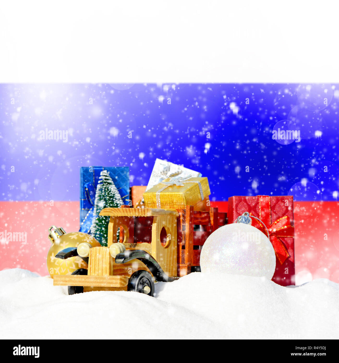 Weihnachten Hintergrund. Spielzeug-LKW mit Geschenken, Neues Jahr Tanne, Kugeln im Schneetreiben und Russische Fahne Stockfoto
