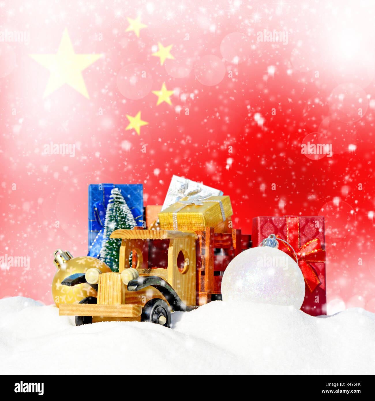 Weihnachten Hintergrund. Spielzeug-LKW mit Geschenken, Neues Jahr Tanne, Kugeln im Schneetreiben und chinesische Flagge Stockfoto