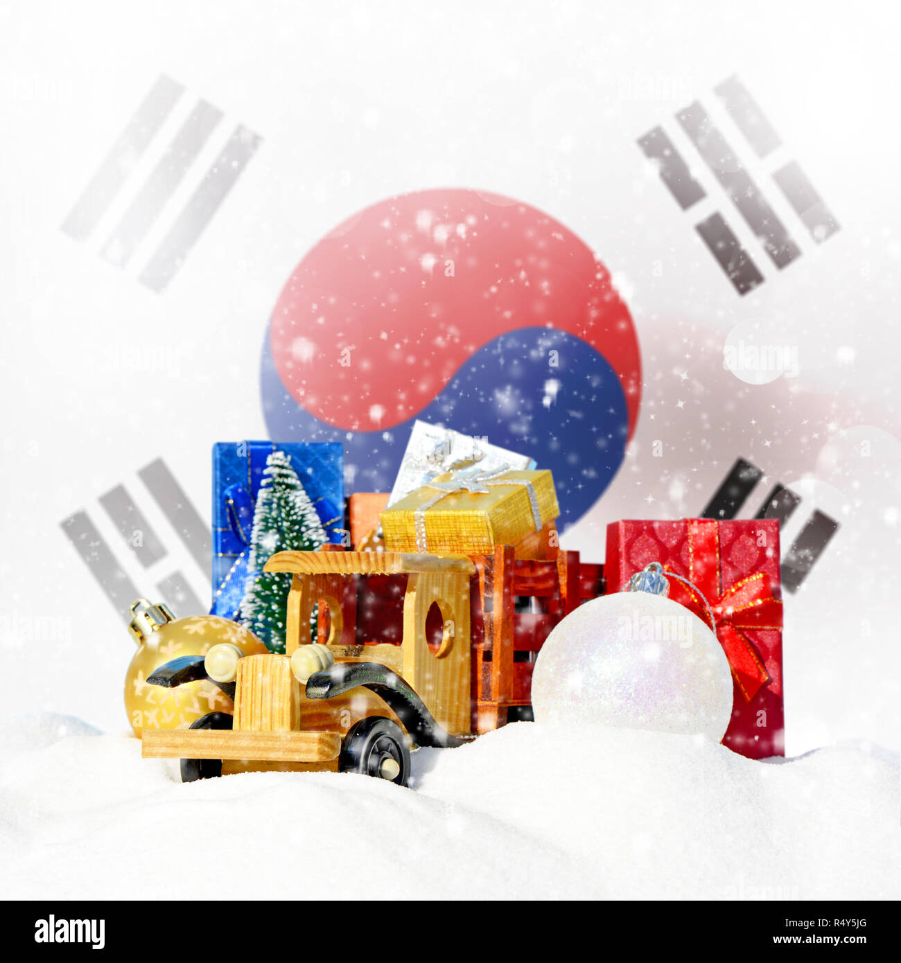 Weihnachten Hintergrund. Spielzeug-LKW mit Geschenken, Neues Jahr Tanne, Kugeln im Schneetreiben und Südkorea Flagge Stockfoto