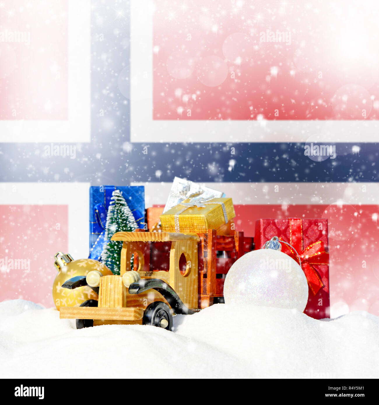 Weihnachten Hintergrund. Spielzeug-LKW mit Geschenken, Neues Jahr Tanne, Kugeln im Schneetreiben und norwegische Flagge Stockfoto