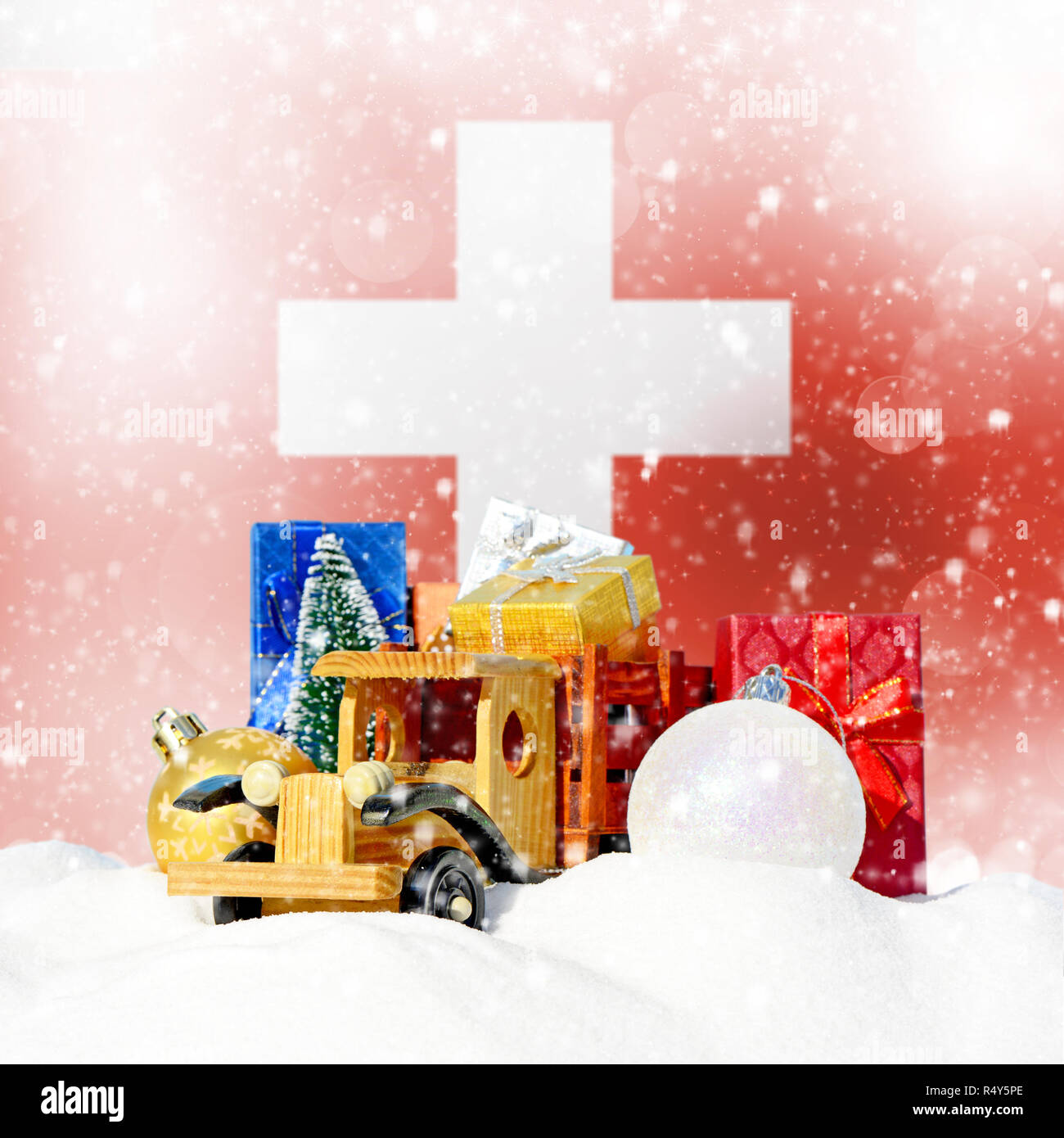 Weihnachten Hintergrund. Spielzeug-LKW mit Geschenken, Neues Jahr Tanne, Kugeln im Schneetreiben und Schweizer Flagge Stockfoto