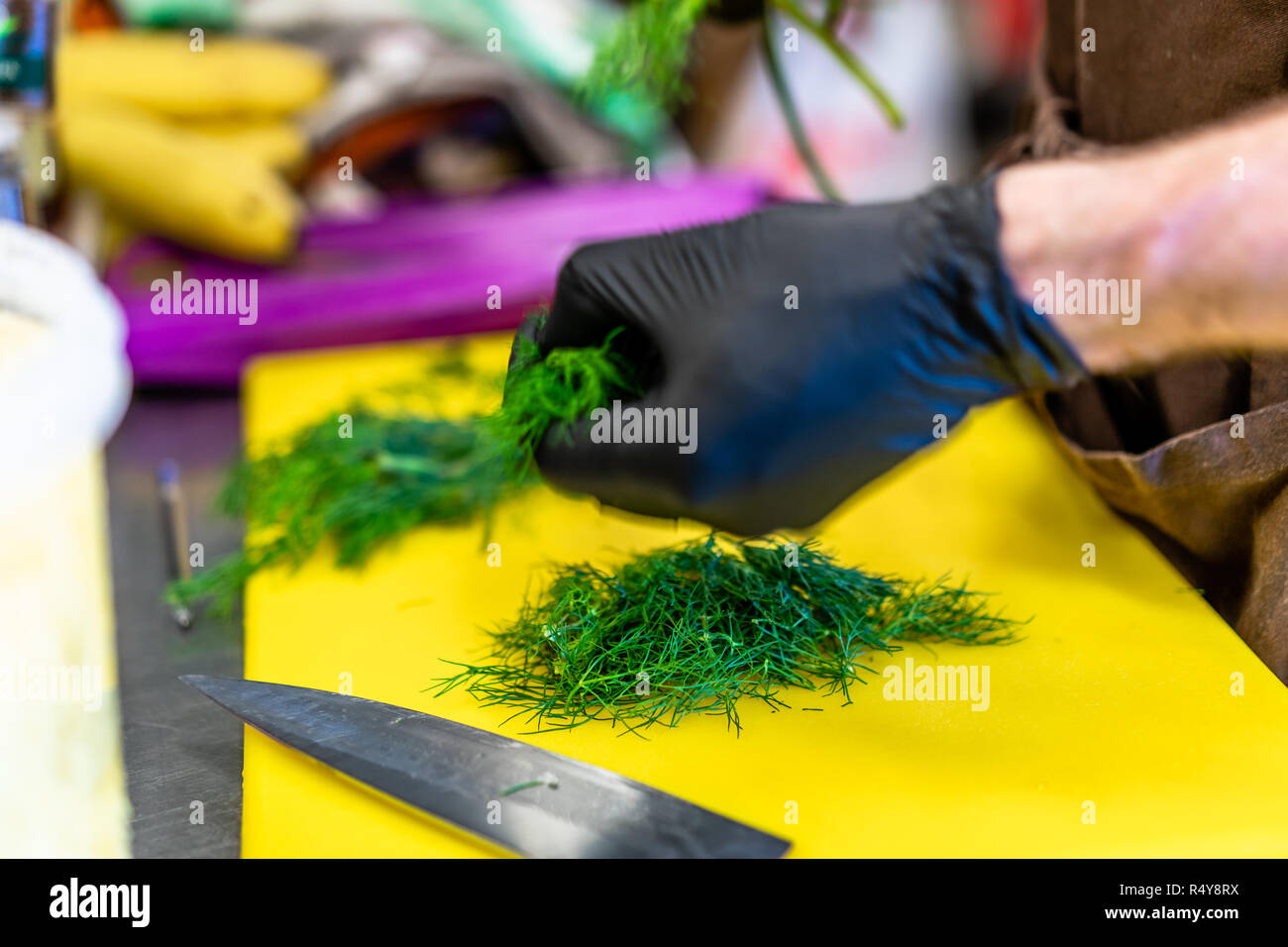 Männliche Chef Schneiden Dill am Gelben Brett - Küche Stockfoto