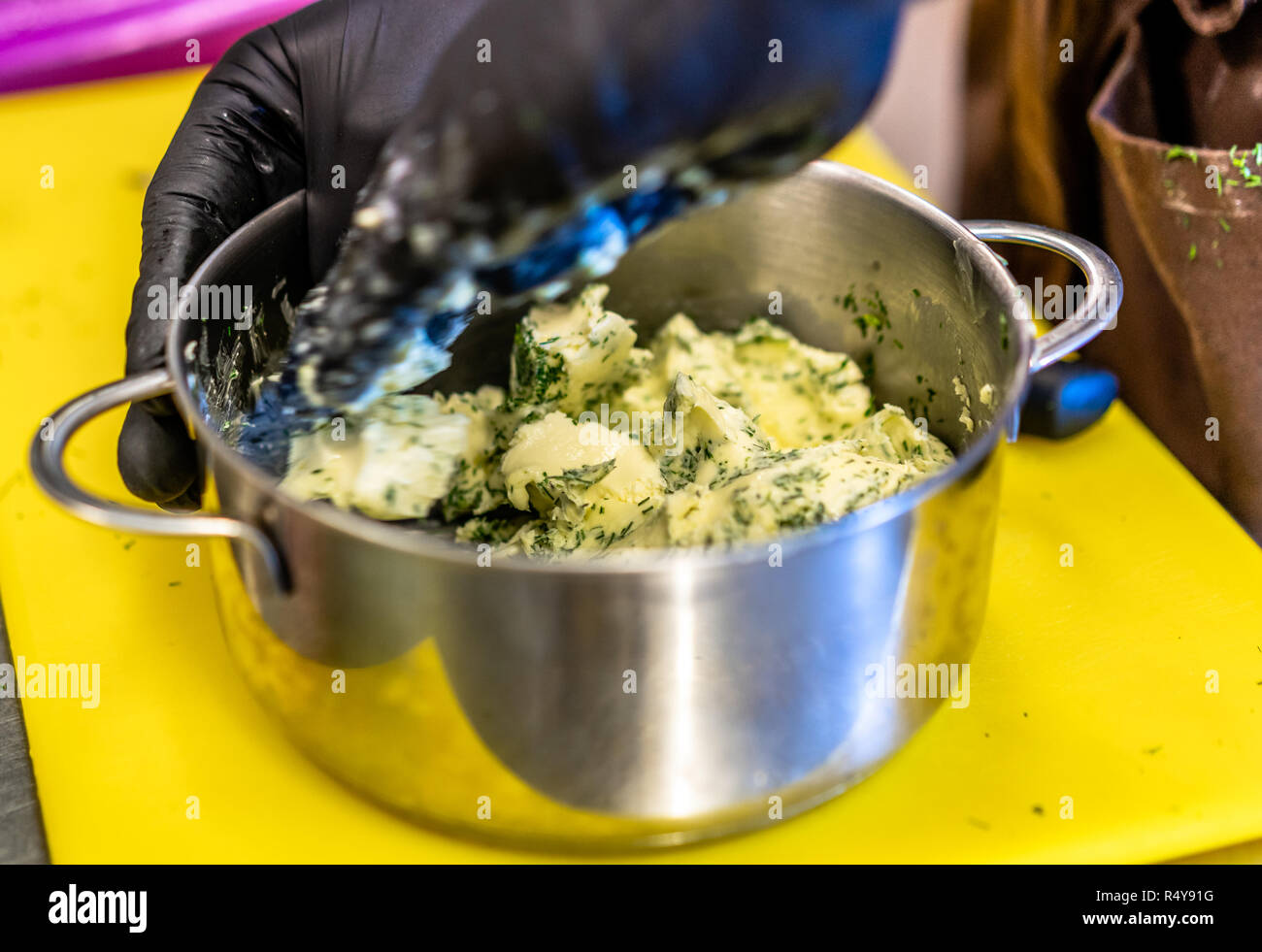 Männliche Chef Mischen geschnittener Dill mit der Butter in der Steel Pot - Küche Stockfoto