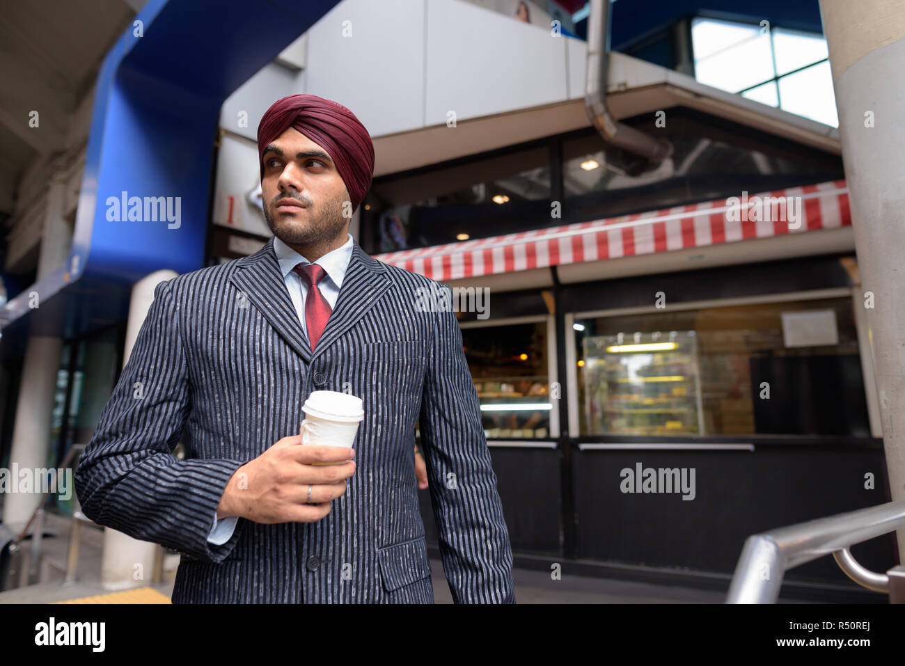 Jungen schönen Indischen Sikh Geschäftsmann holding Einweg Kaffeetasse Stockfoto