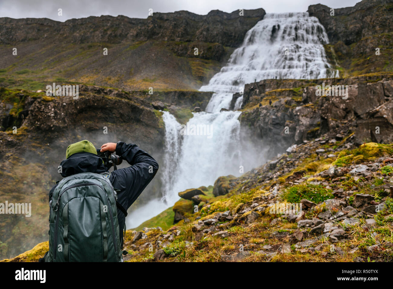Ein Mann nimmt ein Foto bei Dynjandi Wasserfall, dem größten Wasserfall in den Westfjorden Islands Stockfoto