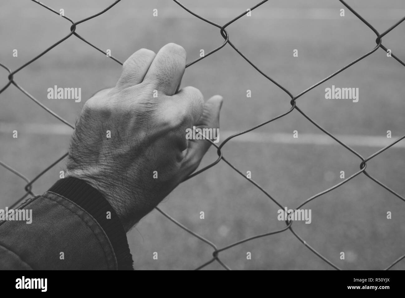 Männliche hand auf chainlink Fence, illegale Einwanderung Konzept Stockfoto