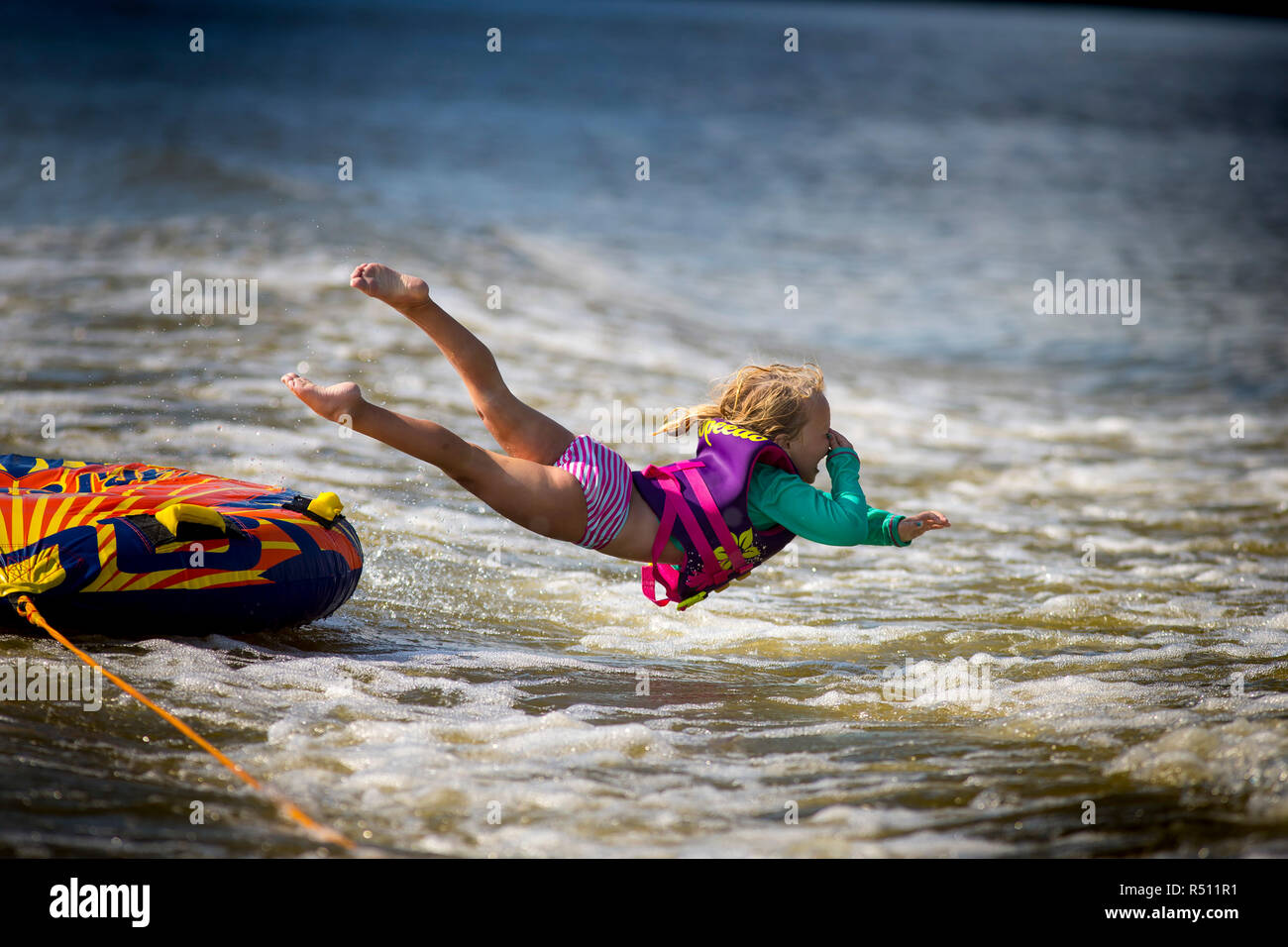 Seitenansicht des Mädchens ein Sprung ins Wasser, während Schläuche auf dem Fluss Stockfoto