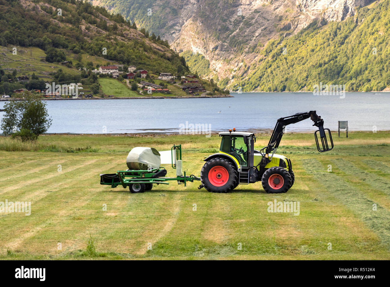 Kleinen Traktor mit einem rundballen Wrapper auf einem Feld in Geiranger, Norwegen. Stockfoto