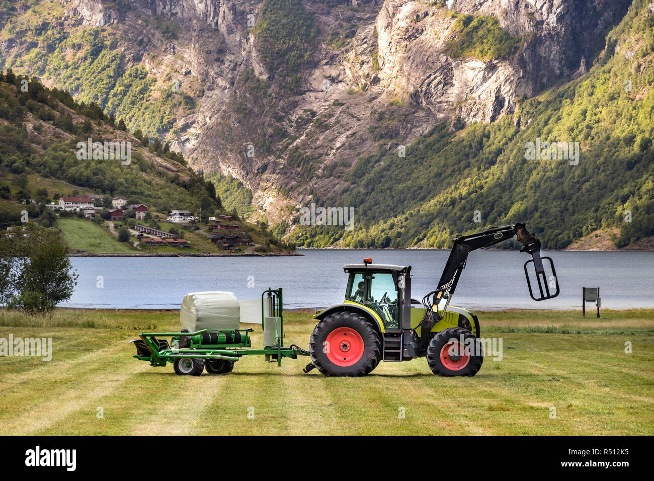 Kleinen Traktor mit einem rundballen Wrapper auf einem Feld in Geiranger, Norwegen. Stockfoto