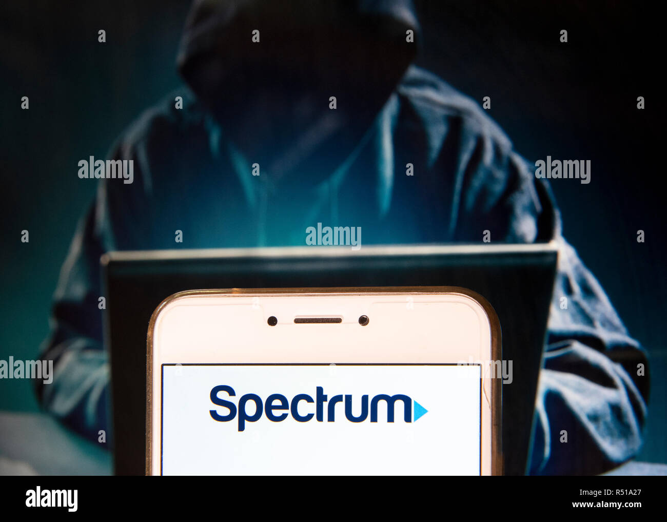 Amerikanische Telekommunikationsunternehmen Spektrum Logo ist auf ein Android mobile Gerät mit einer Abbildung der Hacker im Hintergrund zu sehen. Stockfoto