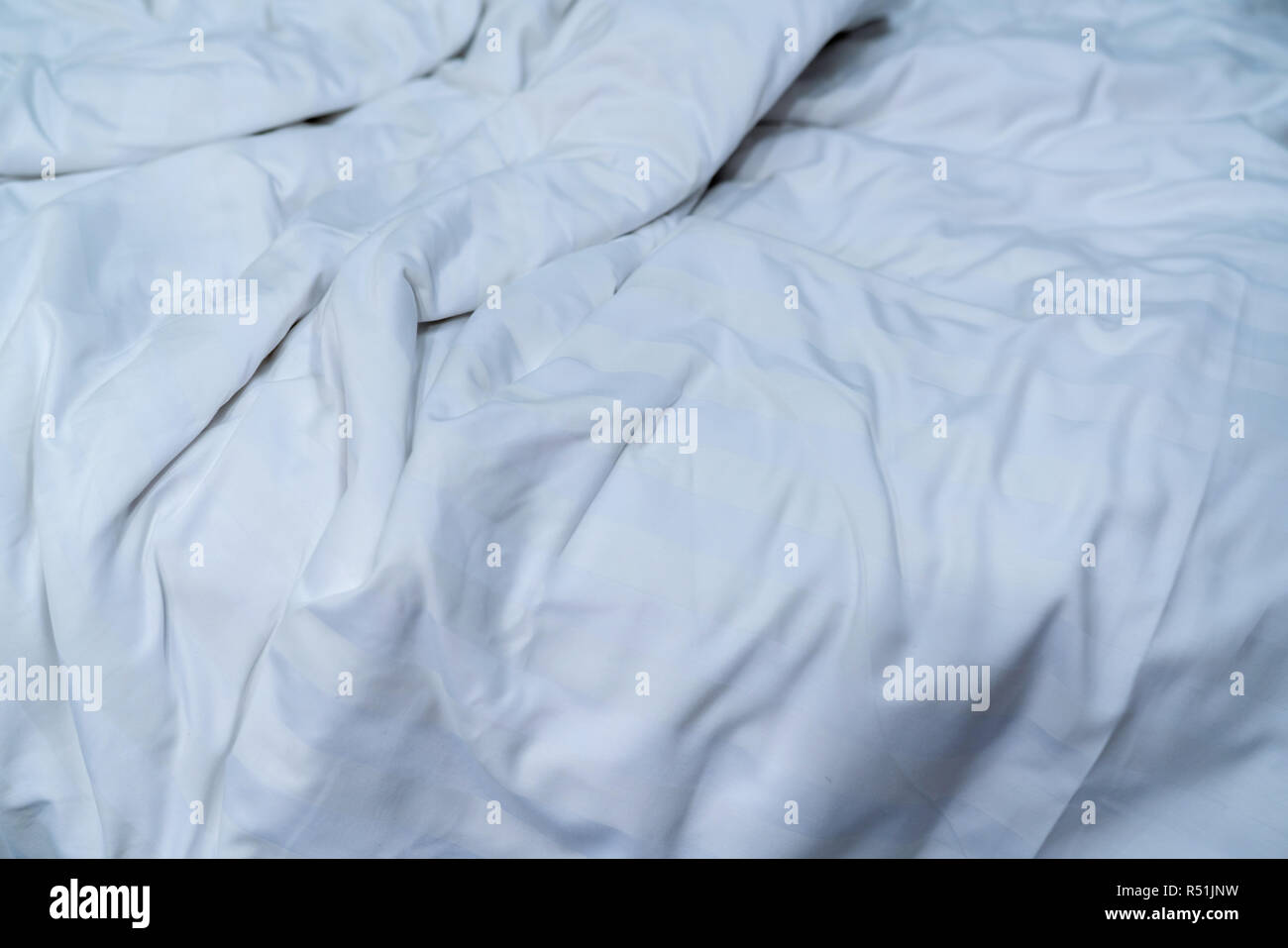 Weiße Bettwäsche Decke im Hotel Schlafzimmer. Nahaufnahme Detail der unordentlichen weiße Decke nach dem Aufwachen am Morgen. Komfortables Bett mit weichen, weißen Bettdecke. Schlafen Stockfoto