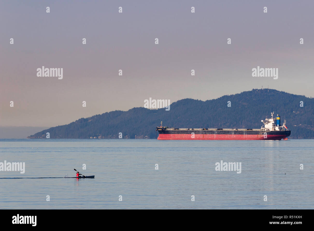 Mann, für morgen Kayak an der English Bay, in Vancouver BC Kanada mit Öltanker und die Hügel im Hintergrund Stockfoto