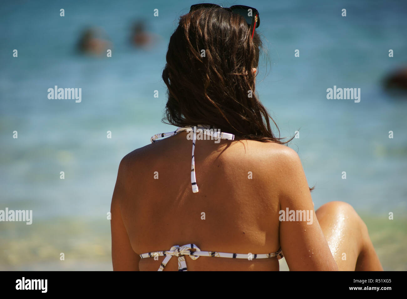 Frau Sitz am Strand Blick auf das Meer, Cala Sassari, Golfo Aranci, Sardinien, Italien Stockfoto