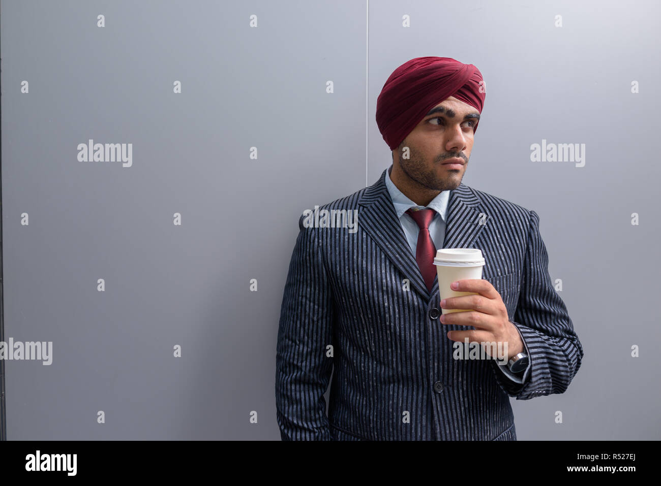 Indischer Geschäftsmann im Freien in Stadt holding Kaffeetasse beim Denken Stockfoto