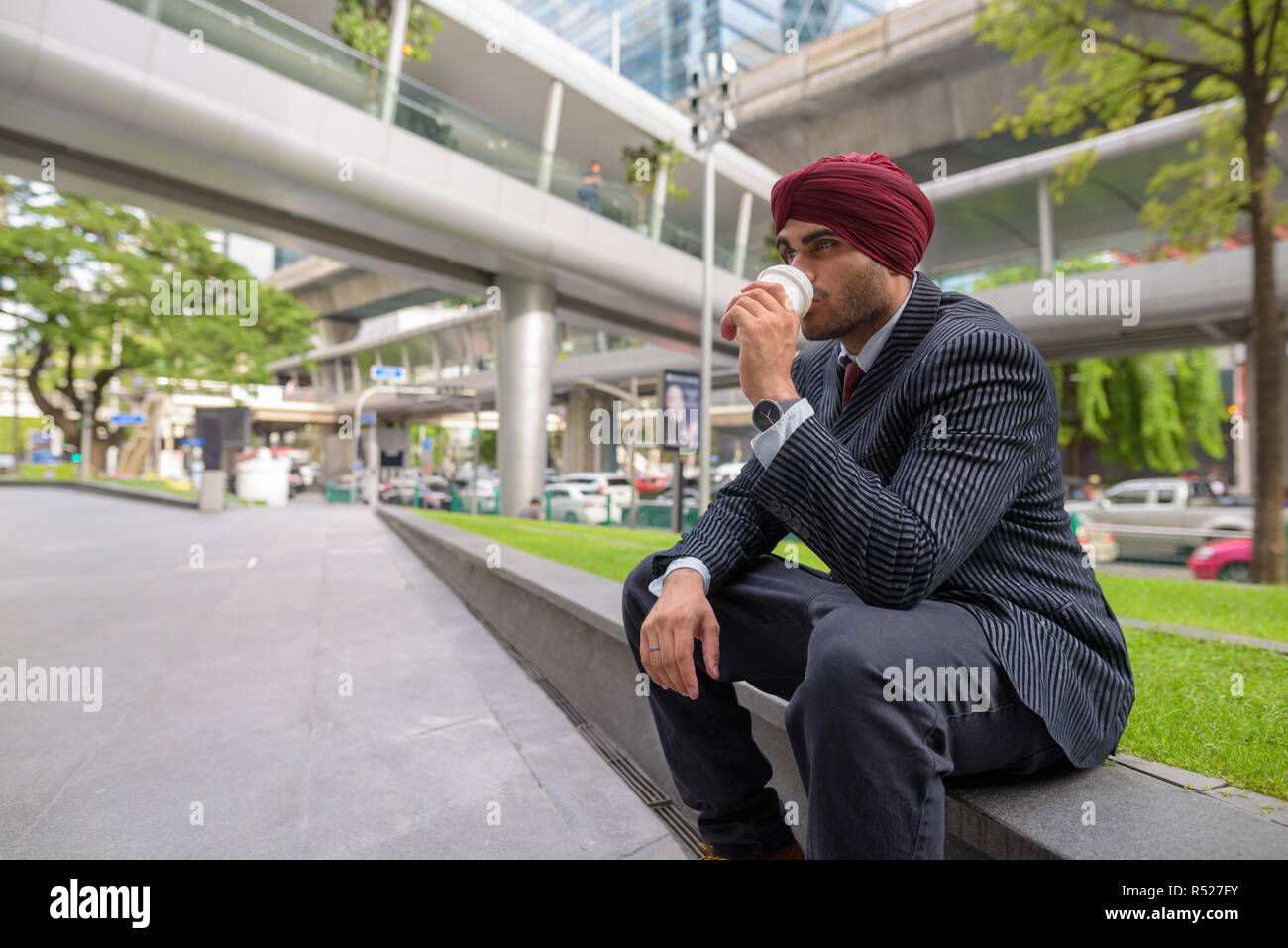 Indischer Geschäftsmann sitzen draußen in der Stadt, während Sie Kaffeepause Stockfoto
