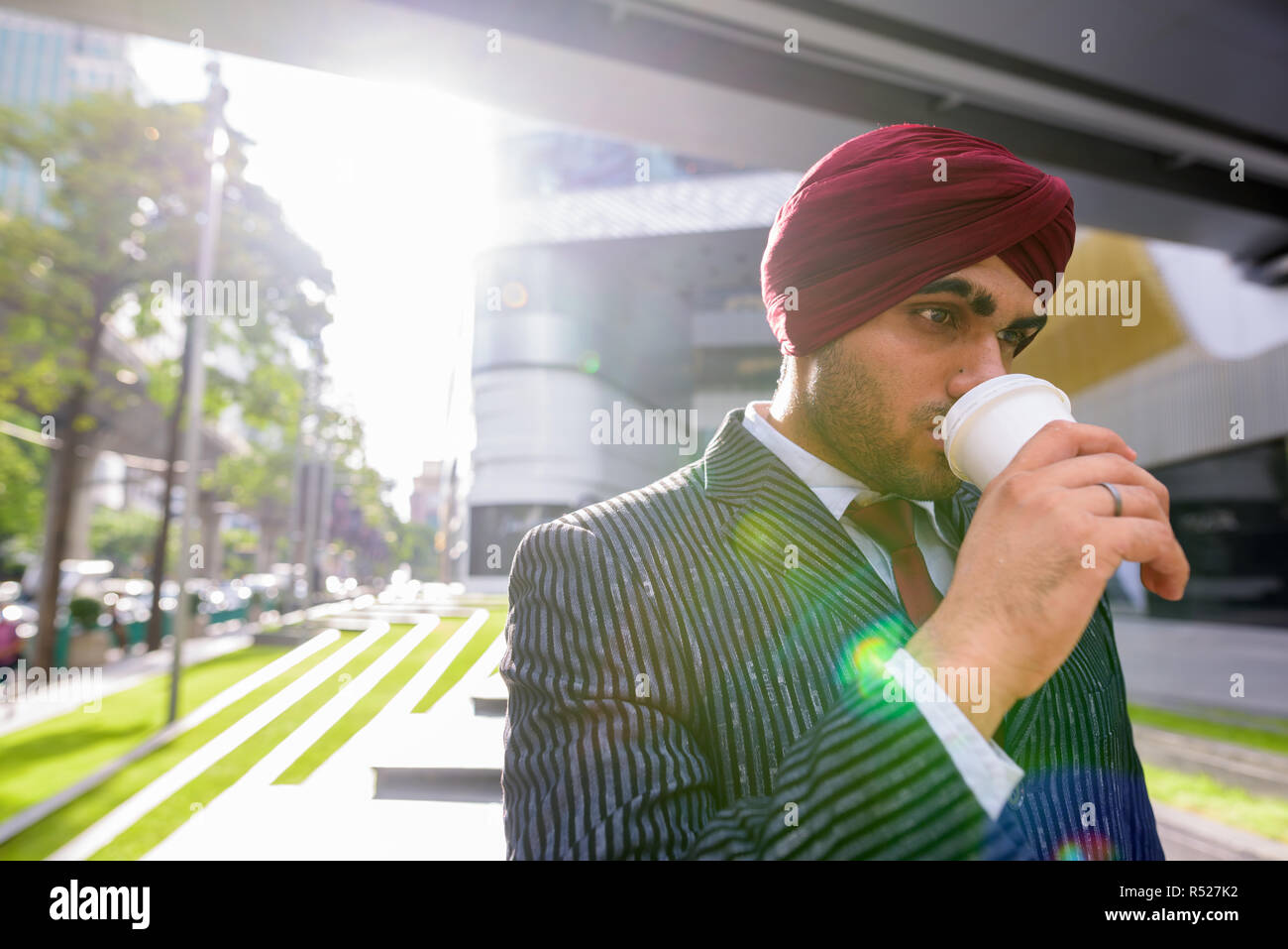 Indischer Geschäftsmann mit Turban im Freien in der Stadt Kaffee trinken Stockfoto