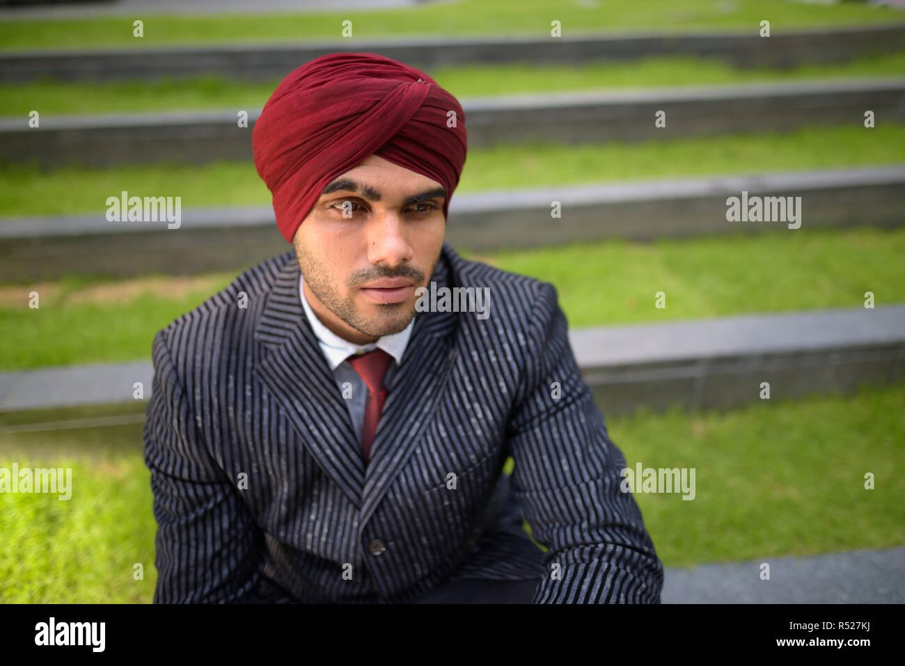 Indischer Geschäftsmann mit Turban sitzt draußen in der Stadt Stockfoto