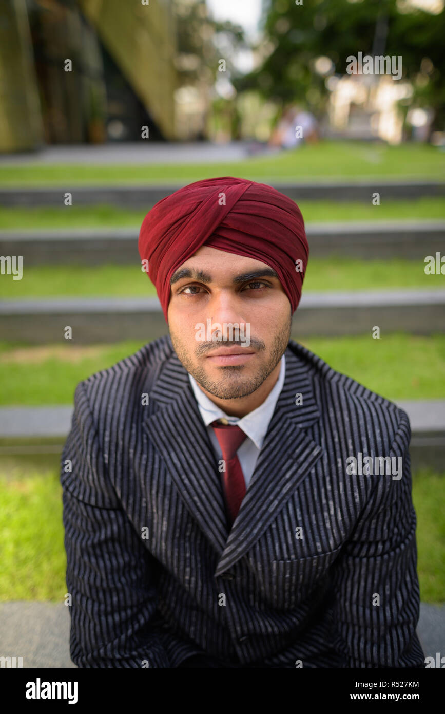 Indischer Geschäftsmann mit Turban sitzt draußen in der Stadt Stockfoto