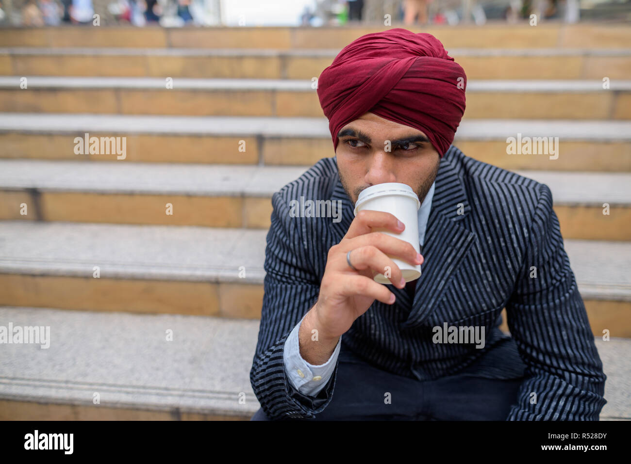 Indischer Geschäftsmann sitzen draußen in der Stadt und trinken Kaffee Stockfoto