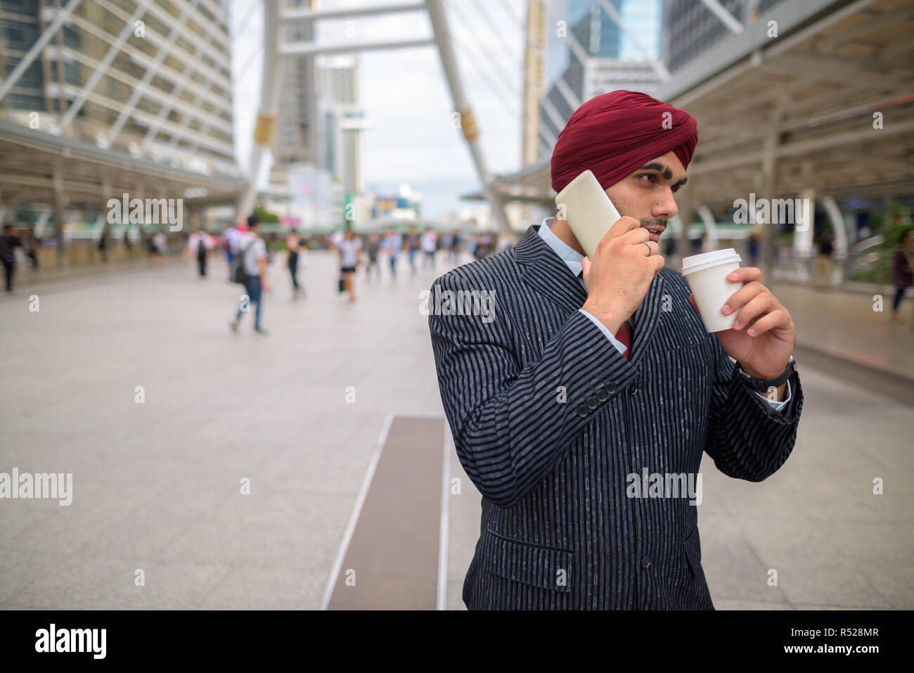 Indischer Geschäftsmann im Freien in der Stadt am Telefon sprechen und Kaffee Stockfoto