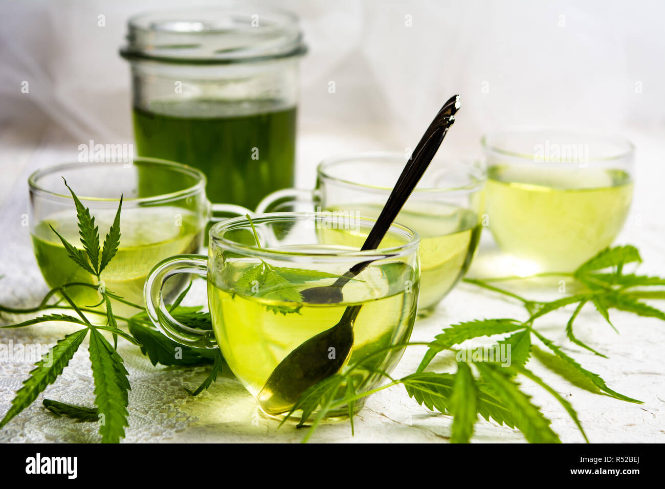 Cannabis Kräutertee serviert im Glas Teetassen mit Marihuana Blätter Stockfoto